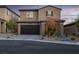 Two-story home with a dark-colored garage door, landscaped yard, and stone walkway at 6877 Painted Morning Ave, Las Vegas, NV 89142