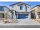 Two-story house with gray siding, blue garage door, and landscaped front yard at 8351 Gold River Ct, Las Vegas, NV 89113