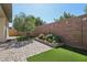 Landscaped backyard with artificial turf, olive tree, and stone wall at 10057 Regency Canyon Way, Las Vegas, NV 89148