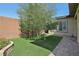 Landscaped backyard with artificial turf, olive tree, and brick pathway at 10057 Regency Canyon Way, Las Vegas, NV 89148