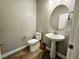 Modern powder room with pedestal sink, toilet, and oval mirror at 10817 San Millan Ave, Las Vegas, NV 89166