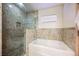 Bathroom with granite shower, bathtub, and window at 2349 Villandry Ct, Henderson, NV 89074