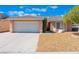 Tan house with a two-car garage and desert landscaping at 2087 Angel Falls Dr, Henderson, NV 89074