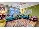 Living room with teal sectional sofa and colorful rug, mid-century modern style at 3616 Via De Leoni Ave, Henderson, NV 89052