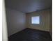 Simple bedroom with dark gray laminate flooring and a window at 4116 Mattray St, North Las Vegas, NV 89032