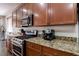 Kitchen features granite countertops, stainless steel appliances, and rich wood cabinets at 3893 Burma Rd, North Las Vegas, NV 89032