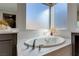 Luxurious soaking tub with a frameless window and stylish fixtures at 2144 Havensight Ln, Henderson, NV 89052