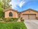 Tan stucco home with a two-car garage, lush lawn, and mature landscaping at 4 Kennesaw Rd, Henderson, NV 89052