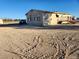 Tan mobile home with a gravel driveway and surrounding land at 1080 Shady Ln, Pahrump, NV 89060