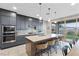 Modern kitchen with gray cabinets, granite island, and stainless steel appliances at 14 Parco Fiore Ct, Henderson, NV 89011