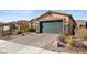 Front view of a house with a dark green garage door and desert landscaping at 2128 Delmar Farms Ct, Laughlin, NV 89029