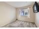 Simple bedroom with carpet flooring, window with blinds, and a wall-mounted TV at 7232 Tealwood St, Las Vegas, NV 89131