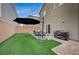 Backyard with patio furniture under umbrella, artificial turf and grill at 5266 Sherwood Forest Ln, Las Vegas, NV 89122