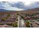 Aerial view of a residential neighborhood with numerous homes, a curving road, and mountain views at 860 Bobcat Run, Mesquite, NV 89034