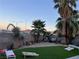 Spacious backyard with grassy area, seating, and cornhole at 1706 Toltec Cir, Henderson, NV 89014