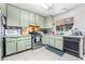 A galley-style kitchen with light green cabinets, stainless steel appliances, and tile flooring at 4765 Marlboro Ct, Las Vegas, NV 89147