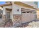 Two-car garage with stone accents and a gray front door at 6138 Villa Lante Ave, Las Vegas, NV 89113