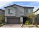 Two-story house with gray siding, brown garage door, and landscaped front yard at 7097 Range Valley St, North Las Vegas, NV 89084