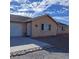 Tan house with white garage door and decorative rock landscaping at 2831 Goldrush St, Pahrump, NV 89048