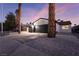 Single-story home with a black garage door and palm trees in the front yard at 5933 Natures Dr, Las Vegas, NV 89122