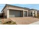 Single-story home with gray exterior, two-car garage, and brick driveway at 8934 Windgate Ranch St, Las Vegas, NV 89166