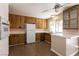 Kitchen with wood cabinets, white appliances, and tile floor at 136 Greenbriar Townhouse Way, Las Vegas, NV 89121