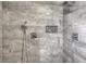 Walk-in shower with a rain showerhead, gray tile walls, and pebble stone floor inlay at 508 Indian Princess Dr # 101, Las Vegas, NV 89145