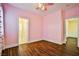 Pink bedroom with wood floors, ceiling fan, and access to bathroom and walk-in closet at 7293 Iron Oak Ave, Las Vegas, NV 89113