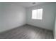 Bright bedroom with gray wood-look laminate flooring, white walls, and a window with blinds at 8348 Stillhouse Ct, Las Vegas, NV 89113