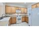 Modern kitchen with oak cabinets, gas range, microwave, and white fridge at 2347 Tranquil Moon St, Henderson, NV 89044