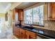 Kitchen sink area with dark granite counters, wood cabinets, and window view at 2 Via Siena Pl, Henderson, NV 89011