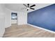 Spacious bedroom featuring a ceiling fan, wood-look floors, and an accent wall at 10960 Vallerosa St, Las Vegas, NV 89141