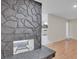 Close-up of a gray stone fireplace with a metal grate and wood flooring at 4475 El Carnal Way, Las Vegas, NV 89121