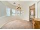 Formal dining room with large windows, chandelier, and neutral carpeting at 9833 Masterful Dr, Las Vegas, NV 89148