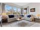 Living room with L-shaped sofa, coffee table, and large windows at 9876 Cullin Range Ave, Las Vegas, NV 89166