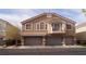 Tan two-story home with gray garage doors and a balcony at 10643 Petricola St # 103, Las Vegas, NV 89183