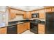 Kitchen with wood cabinets, granite countertops, and black appliances at 3930 University Center Dr # 1003, Las Vegas, NV 89119