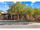 Tan house with brown garage doors and mature trees at 10032 Emerald Pools St, Las Vegas, NV 89178