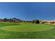 Golf course with green grass, flag, mountains, and trees in the background at 2605 High Range Dr, Las Vegas, NV 89134