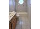 Bathroom with tiled floor and walls, white bathtub, single vanity, and wood cabinet at 1730 Jerome Ln, Pahrump, NV 89048