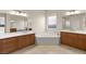 Modern primary bathroom with dual vanities, corner soaking tub, and tiled floors at 10823 Meadow Garden Ct, Las Vegas, NV 89135