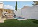 Inviting pool with a covered patio, surrounded by green grass and a white wall at 1179 King Arthur Ct, Henderson, NV 89002