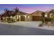 Home exterior with a three-car garage, desert landscaping, and warm lighting at 4541 Largo Cantata St, Las Vegas, NV 89135