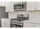 Stainless steel range and microwave in a modern kitchen with white cabinets at 542 Celebratory Pl, Henderson, NV 89011