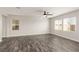 Bright living room with wood-look tile floors, large windows, and a ceiling fan at 10318 Glimmering Star Dr, Las Vegas, NV 89178