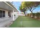 Covered patio, green lawn, putting green, and trees in backyard at 932 Sweeping Vine Ave, Las Vegas, NV 89183