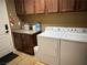 Laundry room with wood cabinets, washer, dryer, and tile floor at 10042 Pipestone St, Las Vegas, NV 89141