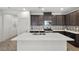 Kitchen island with stainless steel sink, dark cabinets, and white countertops at 11820 Pelican Butte Ave, Las Vegas, NV 89138