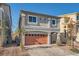 Two-story house with gray siding, orange garage door, and a landscaped front yard at 7881 Tyrell Peaks St, Las Vegas, NV 89139