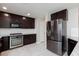 Modern kitchen with dark cabinets, granite countertops, and stainless steel appliances at 6158 Kindlewood Cove Way, Las Vegas, NV 89148